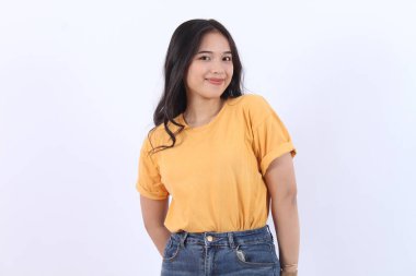 Kendine güvenen neşeli Asyalı kadın kameraya bakıyor sarı tişört giyiyor izole edilmiş beyaz arka plan