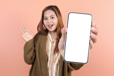 Gülümseyen genç Asyalı güzel bir kadın reklam için cep telefonu ekranı gösteriyor ve şeftali arka planda tek başına elini kaldırıyor. Halk Yaşam Tarzı Konsepti