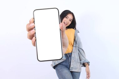 Gülümseyen genç Asyalı kadın, günlük sarı tişörtler giyip reklam için cep telefonunu ve beyaz arka planda izole edilmiş kendine güvenen pozu gösteriyor. Halk Yaşam Tarzı Konsepti