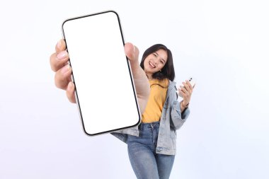 Gülümseyen, genç, Asyalı, günlük sarı tişört giyen, reklam için cep telefonunu gösteren ve beyaz arka planda izole edilmiş bir telefon tutan güzel bir kadın. Halk Yaşam Tarzı Konsepti