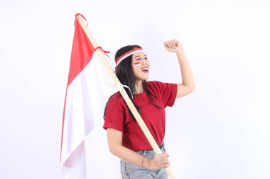 Heyecanlı genç Asyalı kadınlar Endonezya 'nın bağımsızlık gününü 17 Ağustos' ta kutluyorlar. Beyaz arka planda izole edilmiş saç bandıyla kutlama yaparak Endonezya bayrağını tutuyorlar.