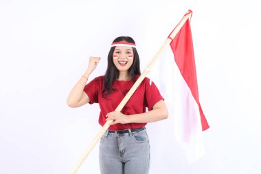 Heyecanlı genç Asyalı kadınlar Endonezya 'nın bağımsızlık gününü 17 Ağustos' ta kutluyorlar. Beyaz arka planda izole edilmiş saç bandıyla kutlama yaparak Endonezya bayrağını tutuyorlar.