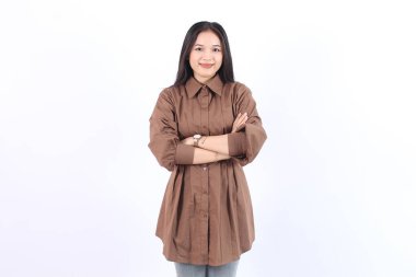 Neşeli Asyalı bir kadın, kendine güveni tam bir Asyalı. Kahverengi elbiseli kameraya bakıyor.