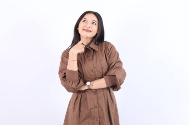 Kahverengi elbiseli güzel bir Asyalı kadın. Çekici kadın poz veriyor, izole edilmiş beyaz arka planda düşünüyor. Asyalı şirin insanlar 
