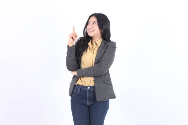 Ceketli mutlu Asyalı genç iş kadını beyaz arka planda izole edilmiş boş yerleri işaret ediyor..
