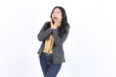 Gri ceketli ve kot pantolonlu kadın şaşırmış görünüyor. O, ceketinin altına sarı bir gömlek giyiyor. İş kadını Asyalı kadın