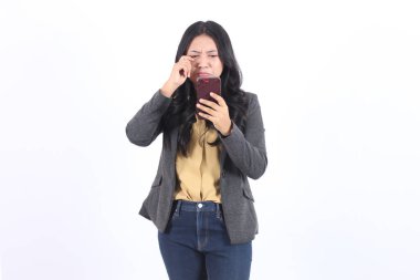 Kadın gri ceket ve kot pantolon giyerken telefonuna bakıyor. Üzücü bir ruh hali. İş kadını Asyalı kadın