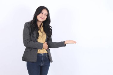 Gri ceketli ve kot pantolonlu kadın bir şey gösteriyor ve işaret ediyor. Pozitiflik ve güven kavramı. İş kadını Asyalı kadın