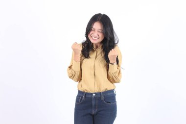 Woman in a yellow shirt and blue jeans is smiling and raising her hands up say yess congratulation. Concept of happiness and excitement. Business asian woman clipart