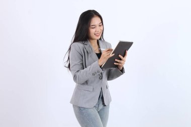 Gri ceketli hippi kadın bir kitabın üzerine yazıyor. Gülümsüyor ve eğleniyor. İş kadını Asyalı kadın