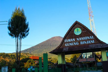 Arkasında dağ olan bir milli park için imza atın. Tabela ahşap ve yeşil çatılı Rinjani, Lombok Endonezya 07 Eylül 2023