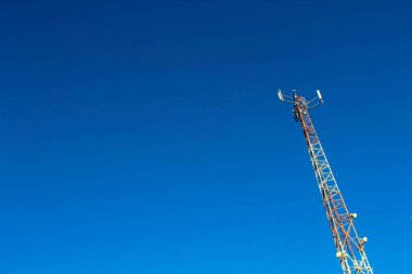 Üzerinde antenler olan uzun kule açık mavi gökyüzünün üzerinde duruyor. Kule engin bir mavi gökyüzü ile çevrilidir, görünürde hiç bulut yoktur. Açıklık ve özgürlük kavramı
