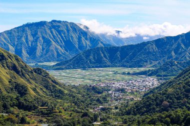 Sembalun Tepesi, Lombok Endonezya sıradağları ve aşağıdaki vadide bir kasaba. Kasaba yeşil tepeler ve ağaçlarla çevrili.