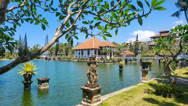 Arka planda evi olan güzel bir gölet. Göl heykeller ve bitkilerle çevrili. Taman ujung, Karangasem Bali, Endonezya 27 Ağustos 2023