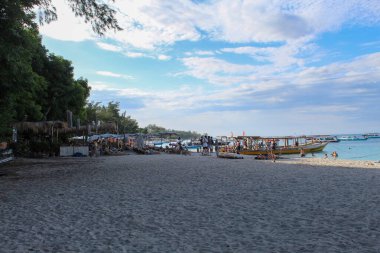 Gili Trawangan 'ın beyaz kumlu plajı, Lombok, Endonezya. Sahile yakın kıyılarda demirlemiş geleneksel tekneler ve arka planda kafeler var..