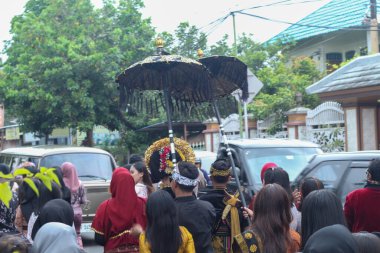 Praya, Lombok, Batı Nusa Tenggara, Endonezya, 19 Nisan 2025. Cidden Asyalı bir adam, geleneksel Lombok kostümleri giyerek Nyongkolan etkinliği sırasında ana caddede yeşil Beleq davulunu çalıyor..