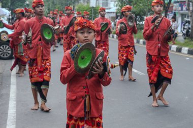 Praya, Lombok, Batı Nusa Tenggara, Endonezya, 19 Nisan 2025. Cidden Asyalı bir adam, geleneksel Lombok kostümleri giyerek Nyongkolan etkinliği sırasında ana caddede yeşil Beleq davulunu çalıyor..