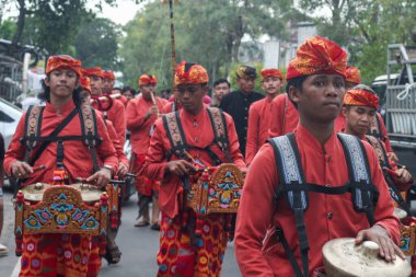 Praya, Lombok, Batı Nusa Tenggara, Endonezya, 19 Nisan 2025. Cidden Asyalı bir adam, geleneksel Lombok kostümleri giyerek Nyongkolan etkinliği sırasında ana caddede yeşil Beleq davulunu çalıyor..