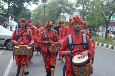 Praya, Lombok, Batı Nusa Tenggara, Endonezya, 19 Nisan 2025. Cidden Asyalı bir adam, geleneksel Lombok kostümleri giyerek Nyongkolan etkinliği sırasında ana caddede yeşil Beleq davulunu çalıyor..