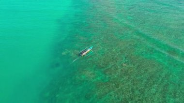 Sersemletici yeşil bir okyanusta, berrak, tropik suların altında görünen mercan resifleriyle uçan bir jet botun hava görüntüsü. Güzel deniz manzarası deniz güzelliğini ve macerayı vurgular.