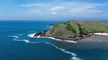 Endonezya, Lombok 'taki yeşil Merese Hill' in insansız hava aracı görüntüleri. Güney okyanusundan gelen dalgalar kıyı şeridine çarpıyor. Gökyüzünden çarpıcı bir kara ve deniz manzarası.