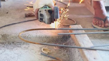 Bir inşaat işçisi, metali kesmek ve parlak kıvılcımlar üretmek için açı öğütücü kullanır. İnşaat alanında sıkı çalışma, kaynak ve imalat..