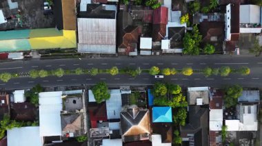 Arka planda ağaçlar ve evler olan şehir caddesinin tepesinden hava manzarası. Sokak bomboş..