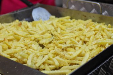 Close up of delicious crinkle-cut fried potatoes. A popular greasy snack or side dish at festivals, fairs, and fast food restaurants.