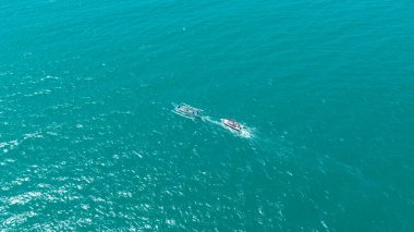 Geleneksel bir roketin ve turkuaz bir denizde yelken açan motorlu teknenin yukarıdan aşağıya insansız hava aracı görüntüsü. Seyahat ve tropikal tatiller için mükemmel bir sahne..