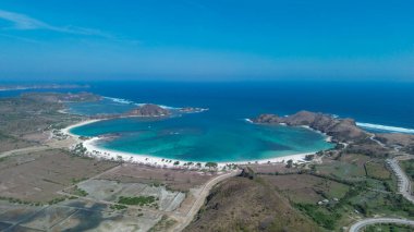 Tanjung Aan, Lombok 'un çarpıcı sahil şeridinin muhteşem insansız hava aracı görüntüsü. Beyaz kum, turkuaz su ve manzaralı tepeleri olan el değmemiş bir cennet..