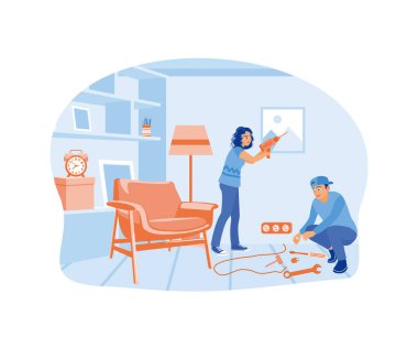 Bir kadın duvara resim asarken bir erkek elektrik tesisatını tamir ediyor. Ev onarımı konsepti. Düz vektör illüstrasyonu.