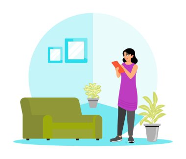 Bir kadın ayakta duruyor ve tablet kullanırken mobilyalı bir odada uygunluk kontrolü yapıyor. Dekor yeşil bir kanepe, dekoratif bitkiler ve çerçeveli duvar sanatı ile süslenmiş. Satılık konsept.