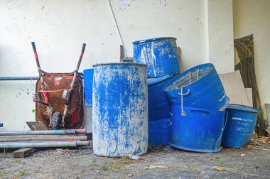 Kullanılmamış su varilleri, çöp kutuları ve el arabaları yığını.