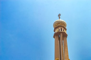 Bir cami minaresi parlak mavi bir gökyüzü arkaplanına karşı
