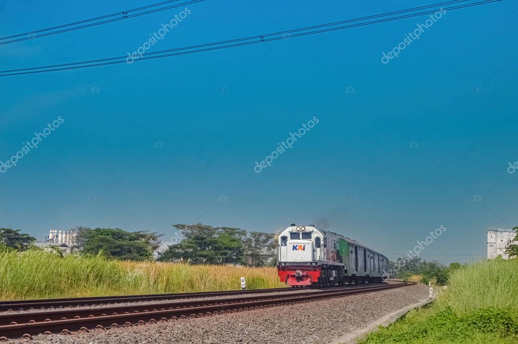 A series of cargo trains with green carriages pulled by a CC201 locomotive made by General Electric belonging to the Indonesian Railway Company, Indonesia, 28 October 2023.