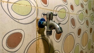 bir su musluğu seramik bir duvara tutturulmuş benek desenli