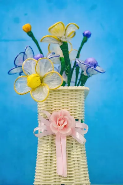 a bouquet of plastic flowers in a flower pot tied with a pink ribbon in the shape of a flower