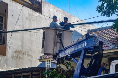 Bayındırlık İşleri Bakanlığı, 19 Aralık 2023 'te Endonezya' da bir hava aracı kullanarak karmaşık telekomünikasyon ve elektrik kabloları düzenliyor..
