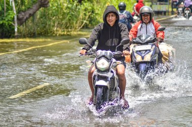 21 Şubat 2024 'te Endonezya' nın Gresik ilçesinde oldukça derin sel sularına düşen bir motosiklet..