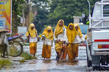 Okuldan eve dönen bir grup ortaokul öğrencisi 21 Şubat 2024 'te Endonezya' nın Gresik Regency kentindeki sel sularını geçti..
