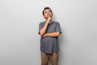 Beyazlar içinde izole edilmiş Asyalı bir adam düşünüyor veya beyin fırtınası yapıyor.