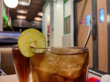 Süslü bir restoranda limonla süslenmiş bir bardak limon çayı kokteyli.