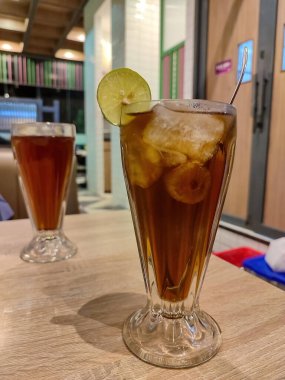 Süslü bir restoranda limonla süslenmiş bir bardak limon çayı kokteyli.