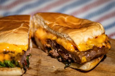 Et, domates sosu, mayonez ve marul ile dolu bir bıçakla bölünmüş bir sığır peynirli burger. Lezzetli görünüyor ve mideni acıktırıyor.