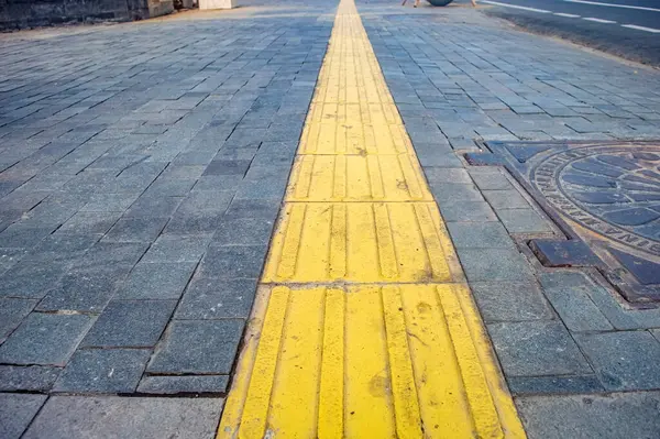 stock image Bright yellow tactile paving for the visually impaired on the sidewalk.