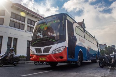 Surabaya 'daki eski bir belediye otobüsü 20 Haziran 2024' te Endonezya 'nın kapısında duran bir otobüs görevlisiyle birlikte hızla şehre doğru ilerliyor..