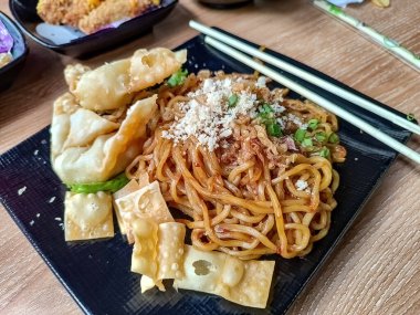 Yanında yemek çubukları olan bir tabak Endonezya baharatlı eriştesi.