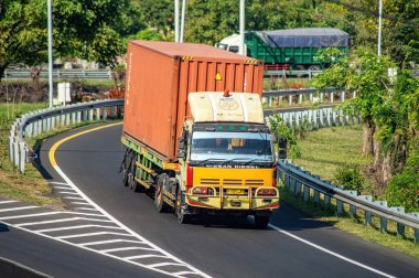 Surabaya Gresik otobanından geçen bir kamyon ya da konteynır kamyonu, 16 Temmuz 2024 'te dünya çapında ihracat ve ithalat için tam yük lojistik taşıyordu..