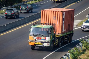 Surabaya Gresik otobanından geçen bir kamyon ya da konteynır kamyonu, 16 Temmuz 2024 'te dünya çapında ihracat ve ithalat için tam yük lojistik taşıyordu..