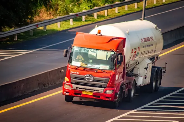 stock image a tank trailer truck carrying Pertamina's LPG or liquid petroleum gas passing fast on the toll road, Indonesia, 16 July 2024.